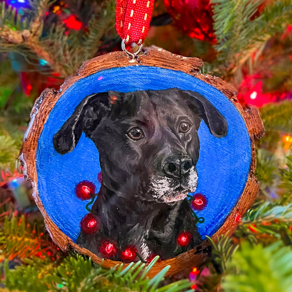 Christmas ornament with a black dog on a blue background, hanging on a decorated tree.