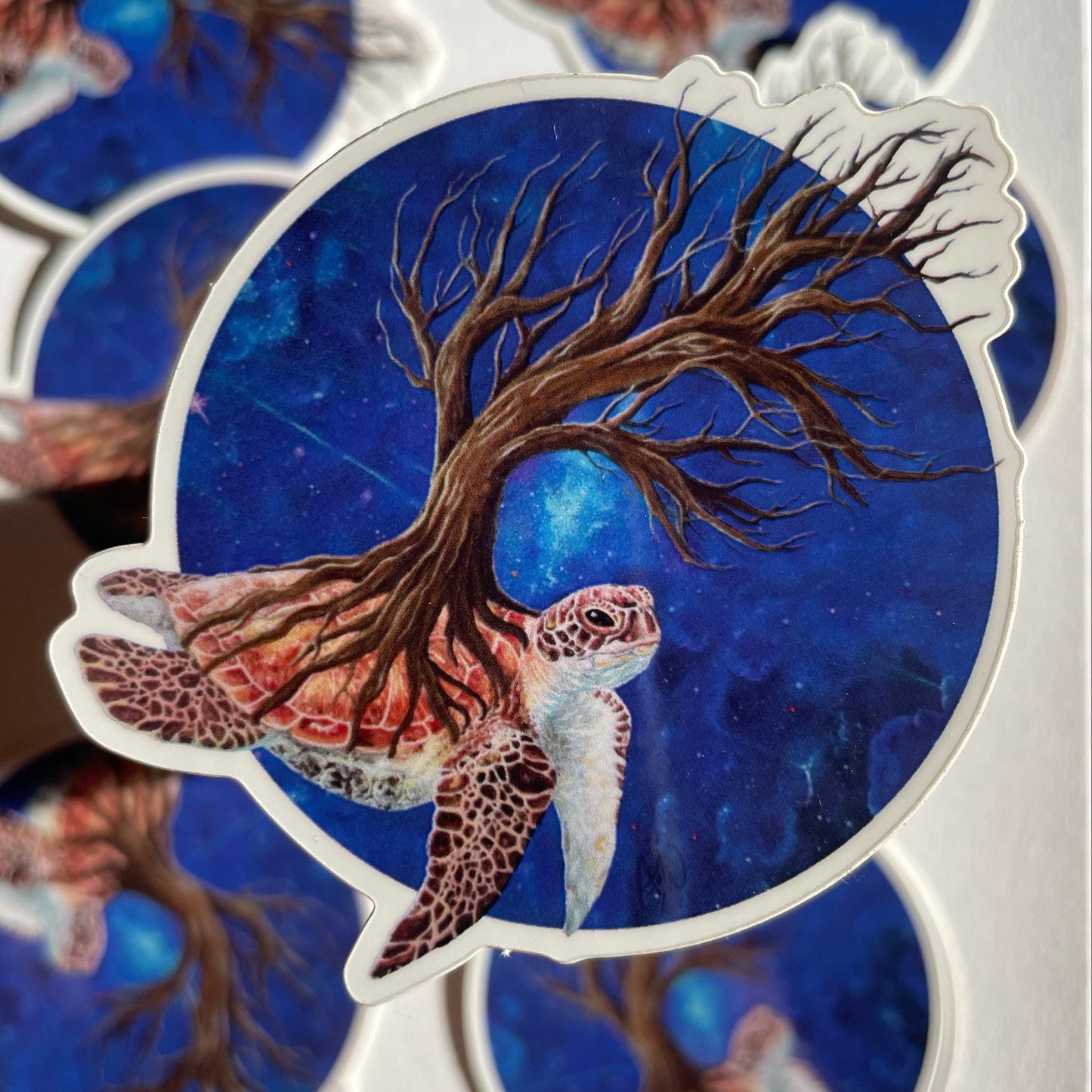 Sticker with a tree and turtle design on a blue background, surrounded by other similar stickers.