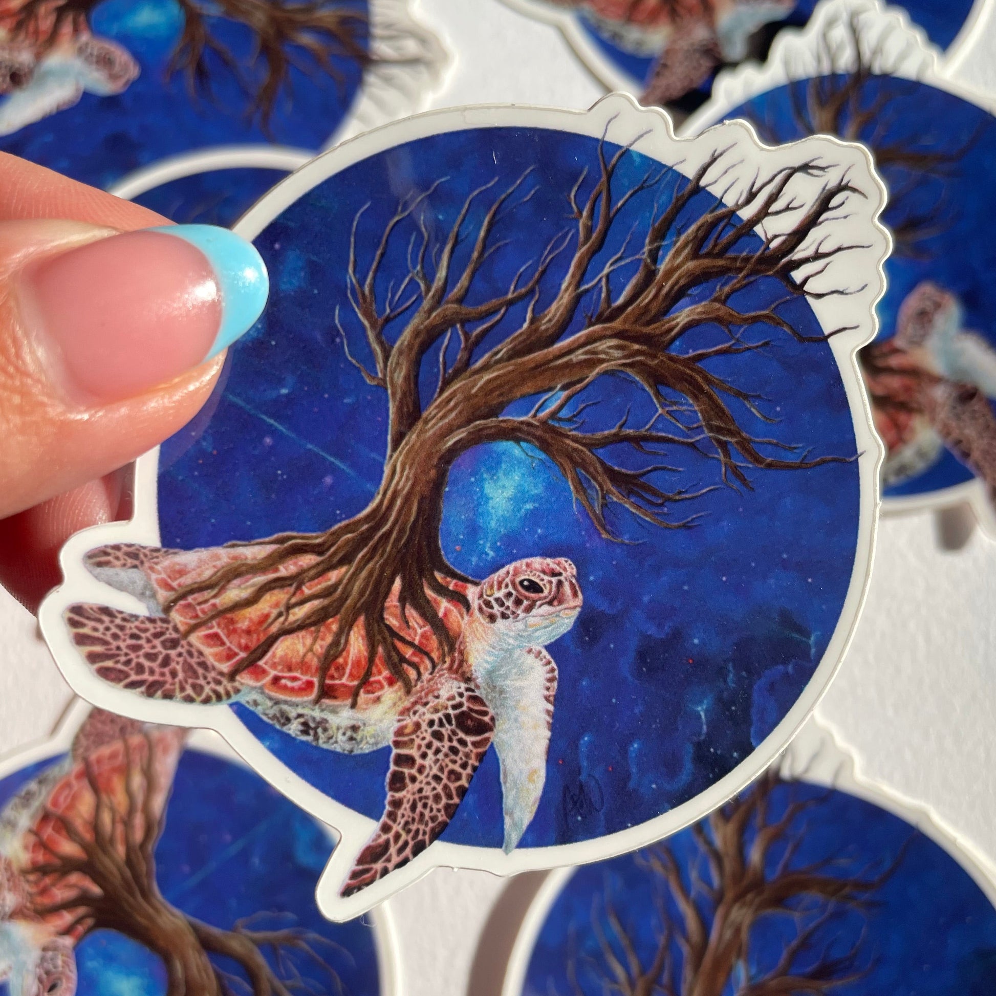 Sticker with a tree and Sea turtle design held by a hand against a white background
